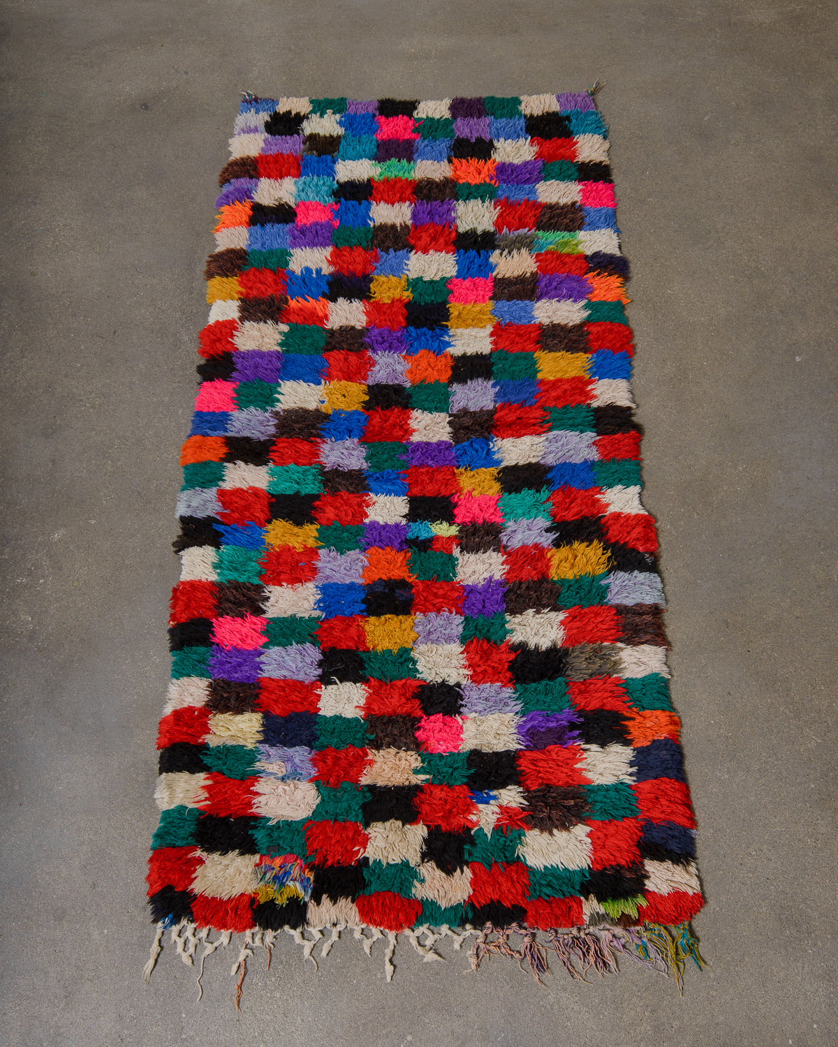 Multicolored checkered rug on a gray concrete floor